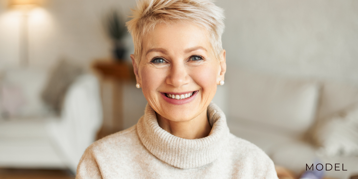 Smiling model in white turtleneck in white living room | periodontal and implant surgeons of houston